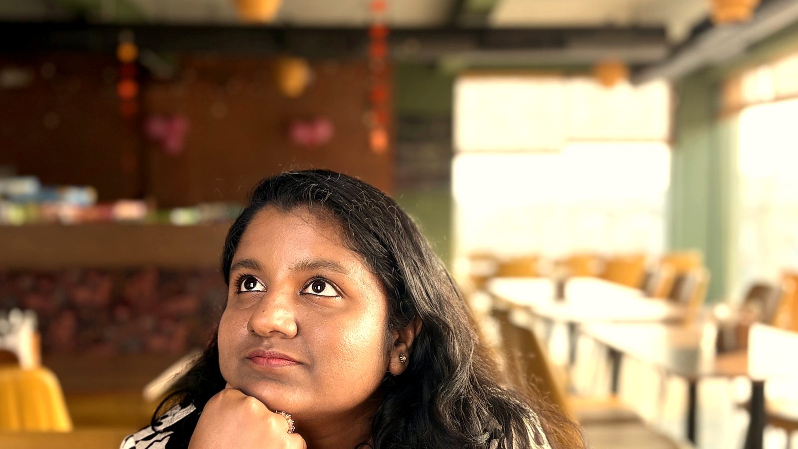 Arthi Rajendran resting her chin on her hand and looking up, deep in thought