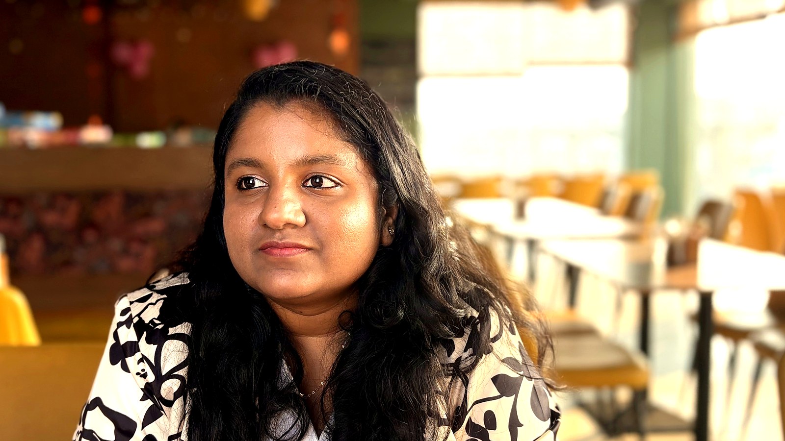 Arthi Rajendran looking at the camera with a calm expression in a bright cafe