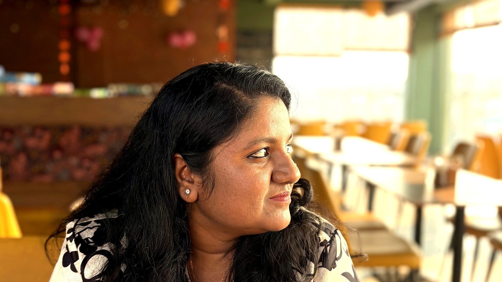 Arthi Rajendran looking aside with a slight smile in a bright cafe